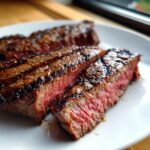 Close-up of perfectly grilled Alton Brown London broil steak, sliced to reveal a juicy pink center and grill marks.