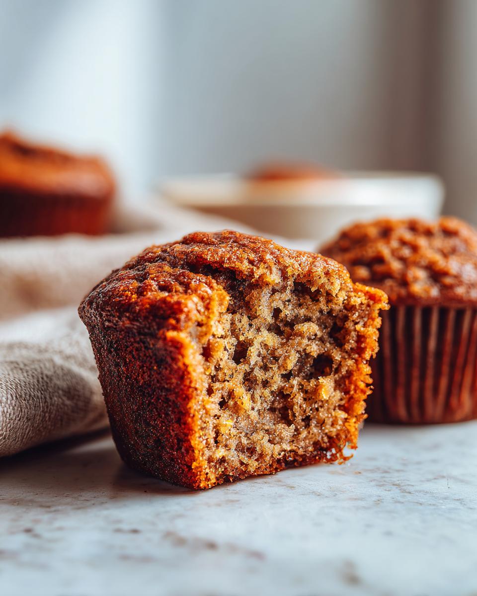Close-up of a delicious banana protein muffin with a bite taken out, showing its moist texture.