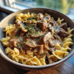 A hearty bowl of Beef Stroganoff served over wide egg noodles, garnished with fresh parsley.