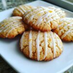 A close-up of several cardamom shortbread cookies drizzled with white icing and sprinkled with orange zest.