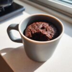A delicious Cottage Cheese Microwave Brownie baked in a grey mug, with a bite taken out.