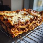 A thick slice of easy lasagna with ricotta, showing layers of pasta, meat sauce, and melted cheese.