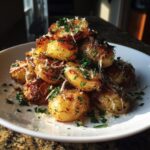 A pile of crispy, golden French onion potatoes topped with shredded cheese and fresh parsley.