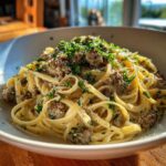A close-up of delicious garlic butter beef linguine topped with fresh parsley and grated cheese.