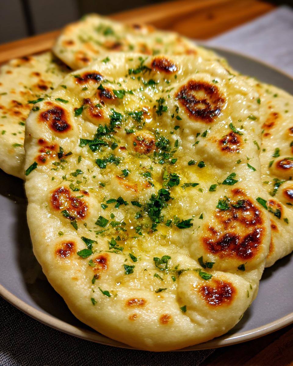 Close-up of freshly baked garlic naan bread brushed with melted butter and sprinkled with chopped parsley.