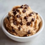 Close-up of a bowl filled with creamy high protein cookie dough studded with mini chocolate chips.