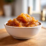 A close-up of a white bowl filled with chunky, spiced homemade applesauce.