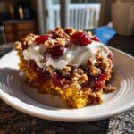 A delicious slice of pecan pie dump cake topped with whipped cream, cherries, and chopped pecans.