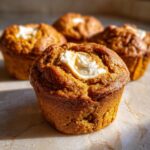 Close-up of a Starbucks pumpkin cream cheese muffin with a swirl of cream cheese filling on top.