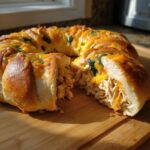 A golden-brown Thanksgiving crescent ring, sliced open to reveal shredded chicken and melted cheese filling.