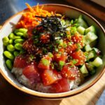 A vibrant Tuna Poke Bowl featuring fresh tuna cubes, edamame, cucumber, shredded carrots, and nori on a bed of rice.