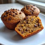 Three delicious chocolate chip protein muffins, one cut in half showing the moist interior texture.
