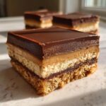 A close-up of a decadent chocolate dream bar, showcasing its layers of chocolate, caramel, and cookie base.