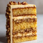 Close-up of a slice of Christmas toffee crunch cake showing three layers of sponge, toffee filling, and cream frosting.