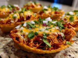 Close-up of crispy chicken tacos filled with shredded chicken, melted cheese, onions, and cilantro.