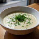 A bowl of creamy high protein cream of potato soup garnished generously with fresh chopped chives.