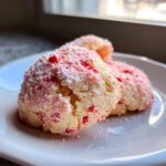 Three soft Maraschino cherry sugar cookies dusted heavily with powdered sugar on a white plate.