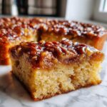 A close-up of a slice of moist Pecan Upside-Down Cake with a glistening caramel pecan topping.