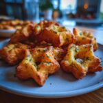 A plate of golden-brown savory churros, shaped like stars and sprinkled with fresh parsley.