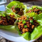 Four servings of amazing chicken lettuce wraps filled with savory ground chicken and topped with fresh green onions.