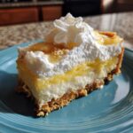 A delicious slice of banana cream cheesecake featuring a graham cracker crust, creamy filling, yellow topping, and whipped cream.