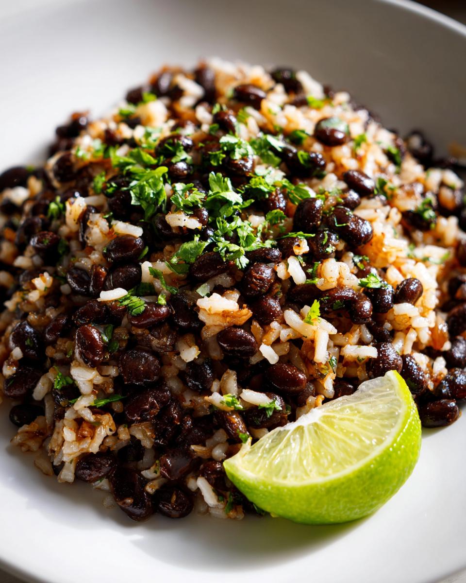 A close-up of a serving of flavorful black beans and rice topped with fresh cilantro and a bright lime wedge.