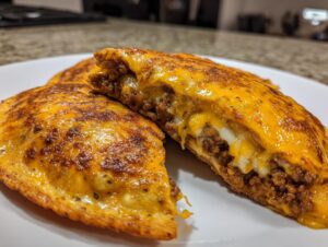 Close-up of cheesy pocket tacos cut in half, showing melted cheese oozing out with seasoned ground beef filling.