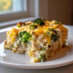 A generous serving of chicken broccoli rice casserole topped with melted cheddar cheese and bright green broccoli florets.