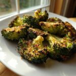 Close-up of crispy, roasted smashed broccoli florets coated in golden breadcrumbs on a white plate.