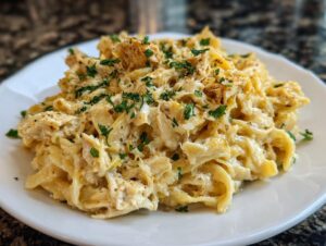 A close-up of a creamy serving of crockpot garlic parmesan chicken pasta topped with parsley.