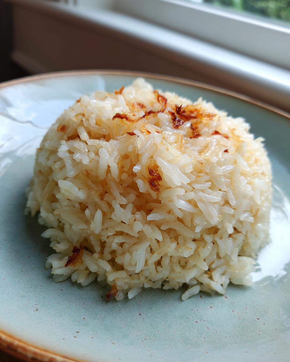 A serving of fluffy butter rice molded into a dome shape and topped with browned bits on a light blue plate.
