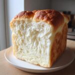 Cross-section view of a perfectly baked japanese milk bread loaf showing its incredibly soft, fluffy white crumb.