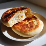 Close-up of a perfectly cooked, fluffy pita bread cut in half showing the airy interior.
