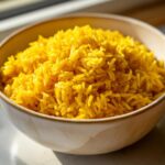 Close-up of a beige bowl filled with vibrant, fluffy turmeric rice, perfectly cooked.