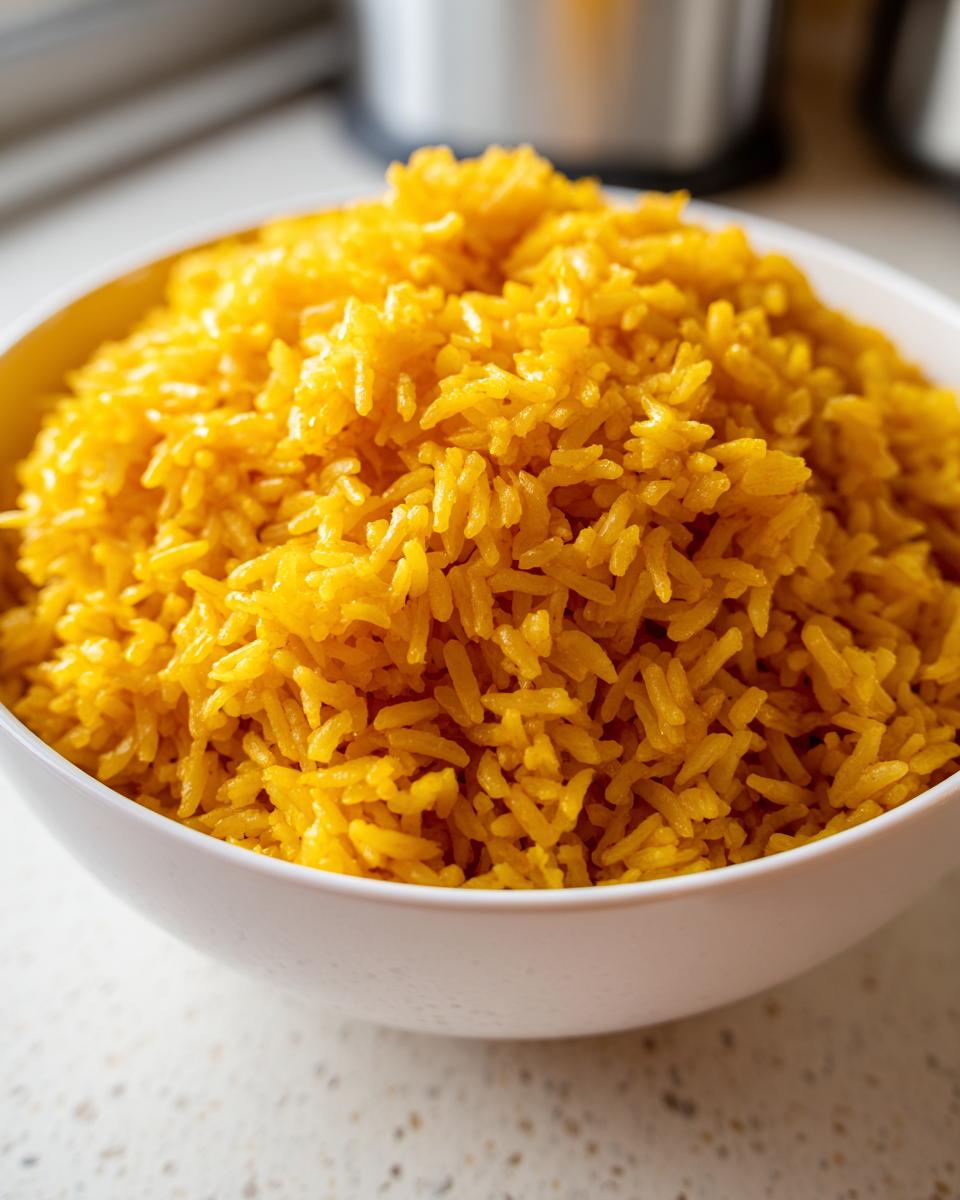 Close-up of a white bowl filled with vibrant, fluffy turmeric rice.