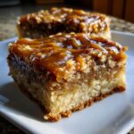 A close-up, tempting shot of a thick slice of pecan pie bars with a gooey caramel topping on a white plate.