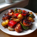 Close-up of glazed Hawaiian chicken pieces mixed with caramelized pineapple, red and green peppers, and onions.