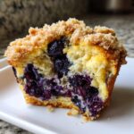 Cross-section of a jumbo blueberry muffin showing moist interior, bursting blueberries, and a thick crumb topping.