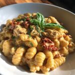 Close-up of Marry Me Chicken Pasta featuring ridged pasta, creamy sauce, chicken pieces, sun-dried tomatoes, and fresh basil.