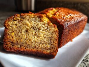 Close-up of a moist slice of sugar free banana bread showing poppy seeds and a golden-brown crust.