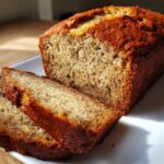 Close-up of a freshly baked loaf of moist sugar free banana bread with two slices cut and resting against it.