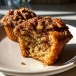 A pecan pie muffin cut in half showing the moist interior and sticky pecan topping.