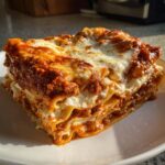 A thick, layered slice of homemade lasagna featuring rich meat sauce and melted cheese topping.