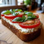 A thick slice of toasted bread topped with creamy cottage cheese toast, sliced tomatoes, and fresh basil leaves.