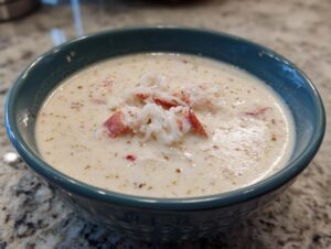 A close-up of a creamy bowl of she crab soup topped with generous chunks of white and red crab meat.