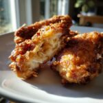 Close-up of a perfectly cooked fried chicken wing, split open to show juicy white meat inside the crispy coating.