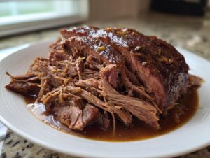 A close-up of tender, shredded Mississippi pot roast covered in rich brown gravy, served on a white plate.