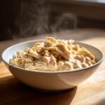A steaming bowl filled with shredded white chicken mixed in a creamy sauce with white beans.