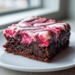 Close-up of a rich, fudgy strawberry brownies square with a pink and white marbled cream cheese swirl topping.