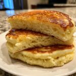 Close-up of three thick, fluffy pancakes stacked, showing the airy interior texture.